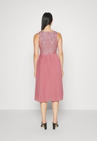 Knee-length dress in blush pink with a sequined bodice, pleated skirt, and a round neckline. Fastens at the back with a zipper.