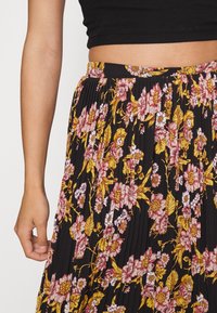 Blommig plisserad kjol med svart botten och rosa samt gula blommor, utrustad med ett bekvämt midjeband och mjuk tygkänsla.