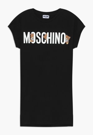 Czarna sukienka Moschino z krótkim rękawem, z białym logo na wysokości klatki piersiowej, zawierająca trzy kreskówkowe misie trzymające znaki "Toy" wkomponowane w napis.
