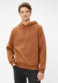 Bruine hoodie met een koord, gemaakt van zachte stof. Bevat een buidelzak en ribgebreide manchetten en zoom. Casual pasvorm, geen zichtbare patronen.