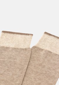 Calze beige fino al ginocchio con una maglia texturizzata, dotate di un risvolto più chiaro e un corpo leggermente più scuro, creando un sottile contrasto di colore.