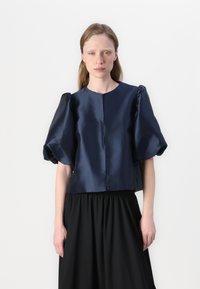 Marineblå sateng crop top med puffede ærmer og rund halsudskæring, parret med en sort samlet nederdel, som skaber en struktureret silhuet.