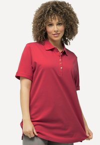 Polo rosso a maniche corte, con colletto abbottonato e vestibilità rilassata. Il materiale sembra liscia e leggera.