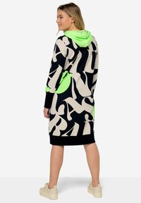 Hooded dress met een zwart, beige en neon groene abstracte patroon. Gemaakt van zacht materiaal, met een relaxed fit en een kangoeroe-pocket.