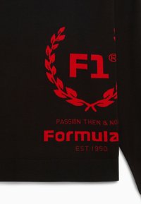 Maglione nero con loghi ricamati rossi: "F1" e "Formula", insieme a "PASSIONE ALLORA E OGGI" e un design di alloro. Orlo a coste.