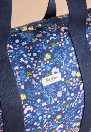 Laivastonsininen Cath Kidston -laukku, jossa on kukka- ja talokuvioita, kullanväriset vetoketjun vetimet ja tukevat tummansiniset kahvat.