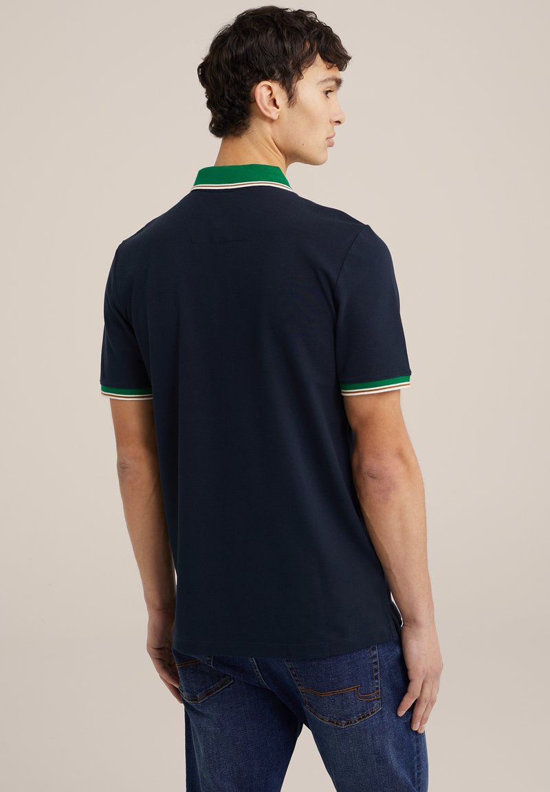 Polo shirt navy avec un col vert et des accents rayés. Manches courtes et coupe classique, fabriqué en tissu doux et texturé.