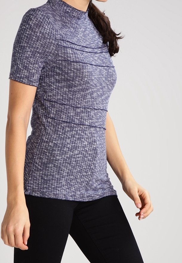 Kortärmad topp i strukturerad marinblått tyg, med horisontella sömdetaljer och hög krage. Matchad med svarta, figurnära byxor.