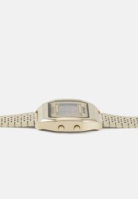 Montre numérique avec un boîtier en acier inoxydable doré et un bracelet en mesh. Dispose d'un cadran rectangulaire, de deux boutons latéraux et d'un affichage numérique.