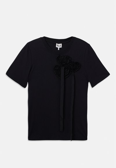 Camisa de manga curta preta com decote redondo e três aplicações florais em tecido texturizado com fitas penduradas no lado frontal esquerdo.