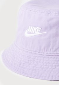 Fialová kšiltovka vyrobená z měkké tkaniny s bílým vyšitým logem Nike. Kšilt je široký s texturovaným povrchem.