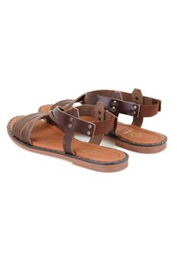 Braune Ledersandalen mit mehreren breiten Riemen, einem gepolsterten Fußbett und einer flachen Sohle mit dekorativer Naht entlang der Ränder.