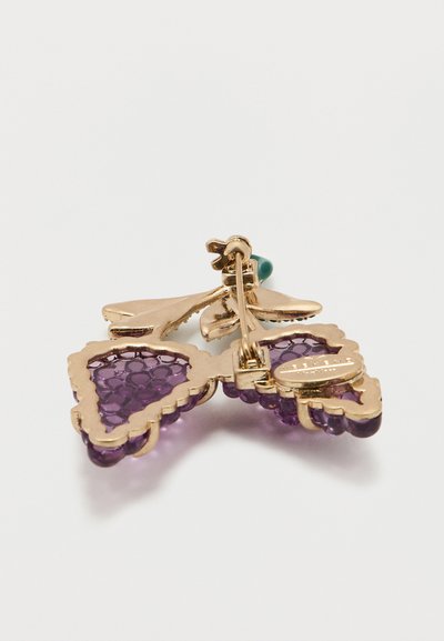 Χρυσό και μοβ καρφίτσα σε σχήμα τσαμπιού σταφύλι με υφή από μοβ γυαλί και πράσινη λεπτομέρεια στην κορυφή, εμφανιζόμενη από την πίσω πλευρά.