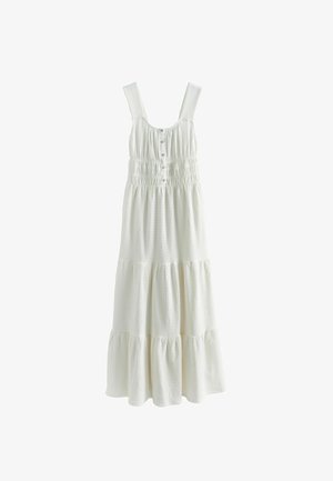 Valge varrukateta maksikleit, mis on laia rihmadega, ees nööbitav, kivilise vöökohaga ja astmelise tekstuuriga kangast seelikuga.