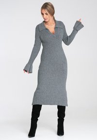 Szary sweterkowy sukienka z dekoltem w serek, długimi rękawami i rozszerzanymi mankietami, sięgająca do połowy łydki, w zestawie z czarnymi kozakami do ud.