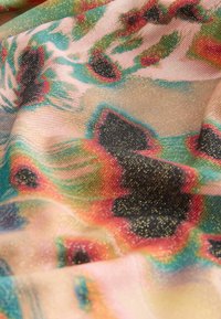 Țesătură ușoară cu model abstract colorat în fire de culoare teal, roșu, negru și auriu, arătând textura și pliuri moi.