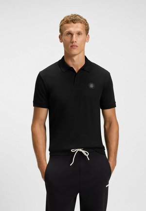 Black polo shirt with a simple design, short sleeves, and a flat collar, featuring a small hexagonal logo on the chest.