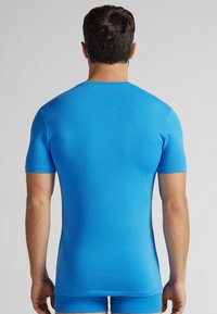 Modrá košile s krátkým rukávem vyrobená z elastického materiálu, přiléhavý střih, hladká textura, bez viditelných vzorů nebo akcentů.