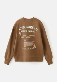 Sweatshirt marrone con la scritta "COME FARE I BISCOTTI DI PAN DI ZENZERO", grafica di un omino di pan di zenzero e dettagli della ricetta stampati. Realizzato in morbido tessuto testurizzato.