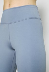 Leggings elásticos de cintura alta en un color azul claro, que presentan una textura suave y costuras planas para mayor comodidad. Sin bolsillos ni detalles adicionales.
