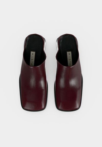 Ζευγάρι μπορντό δερμάτινα παπούτσια mule χωρίς κορδόνια με τετράγωνα μύτες και μαύρες εσωτερικές σόλες με την ετικέτα «MIISTA» σε λευκό φόντο.