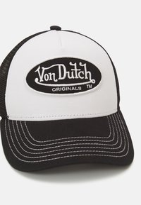 Lastbilshatt med vit front, svarta nät-sidor och bak, prydd med en broderad svart oval logotyp som står "Von Dutch Originals."