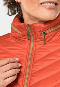 Rode pufferjack met een hoge kraag, voorzien van gouden hardware en diagonale stiksel. Inclusief ritssluiting en twee zijzakken.