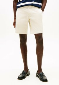 Beige bomullsshorts med vanlig passform, sidelommer og en søm som ligger rett over knærne, paret med svarte loafers.