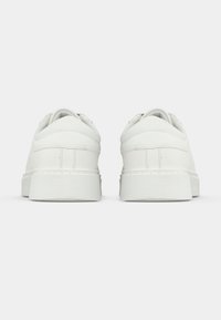 Valged tennisjalad sileda nahkpealse, ümarate varvaste ja pehmendatud kaelusega. Omavad tekstuurset talla ja diskreetset õmblusdetaili.