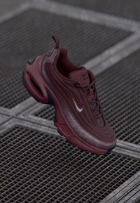 Nike Air Max 97 sneakers in deep burgundy. Features smooth leather material, wavy design, black accents, and a visible air unit in the sole.