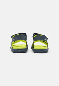 Sandalias de agua en azul y amarillo, con diseño de talón abierto, correas ajustables y suelas de goma texturizada. Visible la marca Geox.