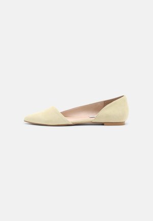 Chaussure plate en daim beige à bout pointu, côté intérieur ouvert et petit talon sur fond blanc uni.