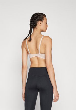 Lys rosa bh med justerbare stropper og baklås, sammen med høyt liv sorte leggings som viser en jevn tekstur.