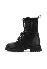 Zwarte combatboot tot halverwege het scheenbeen met dikke profielzool, metalen oogjes, veters om de enkel gebonden en een aantreklabel aan de achterkant.