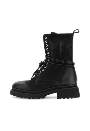 Černé bojové boty do poloviny holeně s tlustou podrážkou s výrazným vzorem, kovovými očky, tkaničkami zavázanými kolem kotníku a poutkem na zadní straně.