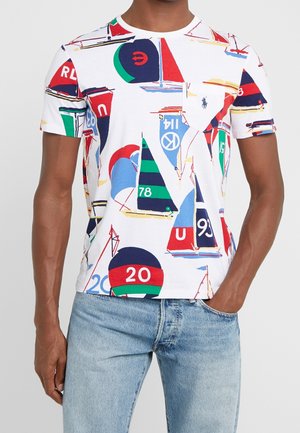Hvid t-shirt med et farverigt sejlskibsmønster i blå, rød, grøn og sort. Rund halsudskærning og kortærmer, lavet af blød bomuld.