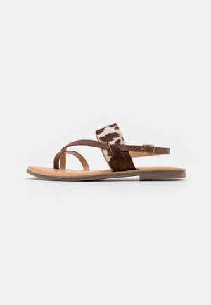 Sandales en cuir marron avec un accent imprimé vache, design à bouts ouverts, fines brides et semelles plates. La texture est lisse avec un dessus à motif.
