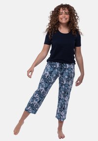 T-paita lyhyillä hihoilla merensinisenä, yhdistettynä kukkakuosisisiin vaaleansinihin cropped-housuihin, joissa on kiristysnyöri vyötäröllä ja pehmeä kangas.