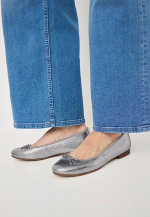 Silver ballet flats with a smooth finish, rounded toe, and a decorative bow accent. Paired with light denim wide-leg pants.