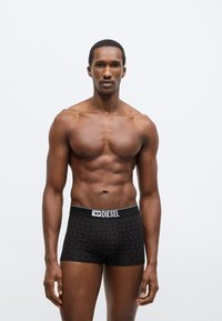 Fekete boxermgatya puha, rugalmas anyagból, márkás elasztikus derékpánttal és apró logókból álló diszkrét mintával.