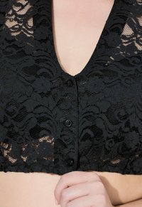 Schwarzes Spitzen-Crop-Top mit tiefem V-Ausschnitt, das mit floralen Mustern verziert ist, kurze Ärmel hat und drei schwarze Knöpfe vorne trägt.