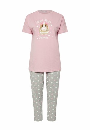 Camiseta de algodón de color rosa con un gráfico de un cobayo y texto, combinada con pantalones de pijama grises que tienen pequeños patrones de corazones rosas y blancos.
