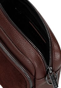 Bruine leren en suède tas met een ritsluiting, textuurafwerking en een zwarte binnenvoering. Bevat hardware in zilverkleur en heeft een compact ontwerp.