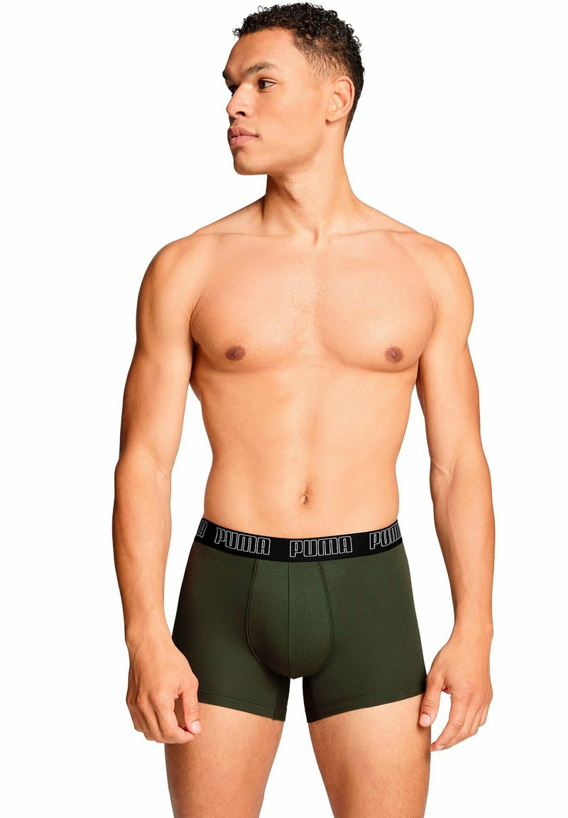 Bóxer de algodón verde con cinturilla de logo negro de Puma. Diseño ajustado, longitud a mitad del muslo, textura suave y sin patrones ni acentos visibles.