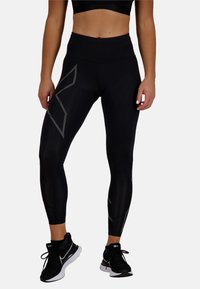 Czarne legginsy z wysokim stanem, wykonane z elastycznego materiału, z teksturowaną powierzchnią i odblaskowymi szarymi akcentami po bokach.