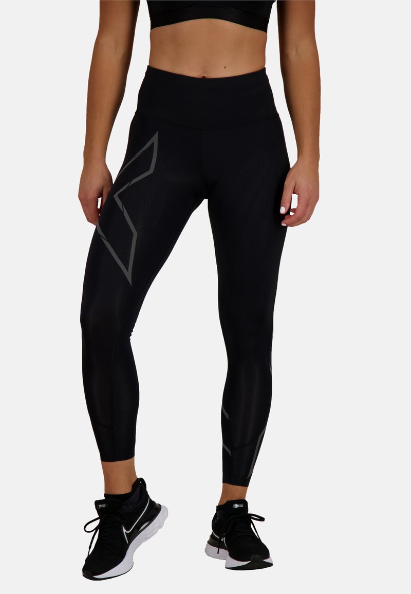 Czarne legginsy z wysokim stanem, wykonane z elastycznego materiału, z teksturowaną powierzchnią i odblaskowymi szarymi akcentami po bokach.