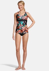Tankini multicolore avec un motif abstrait vibrant en orange, vert et noir ; il possède un buste ajusté et un bas de bikini noir.