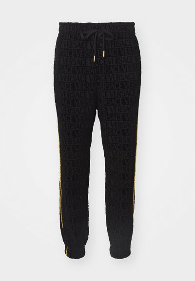 Svarta sweatpants med ett heltäckande texturerat mönster av ordet "VERSACE." Sidsömmar i gult med elastiska muddar och midjeband.