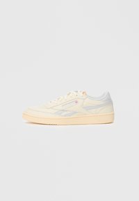 Kreemja ja heledat halli madala profila sneakersid, mis on valmistatud siledast nahast, sisaldavad diskreetset brändimist ja kummist tallat, ümarate varvaste ja nööbitava disainiga.