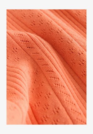 Korallenfarbiger Strickstoff mit strukturierten Mustern und vertikalen Rippen, der eine weiche Textur mit zarten Lochmustern zeigt.